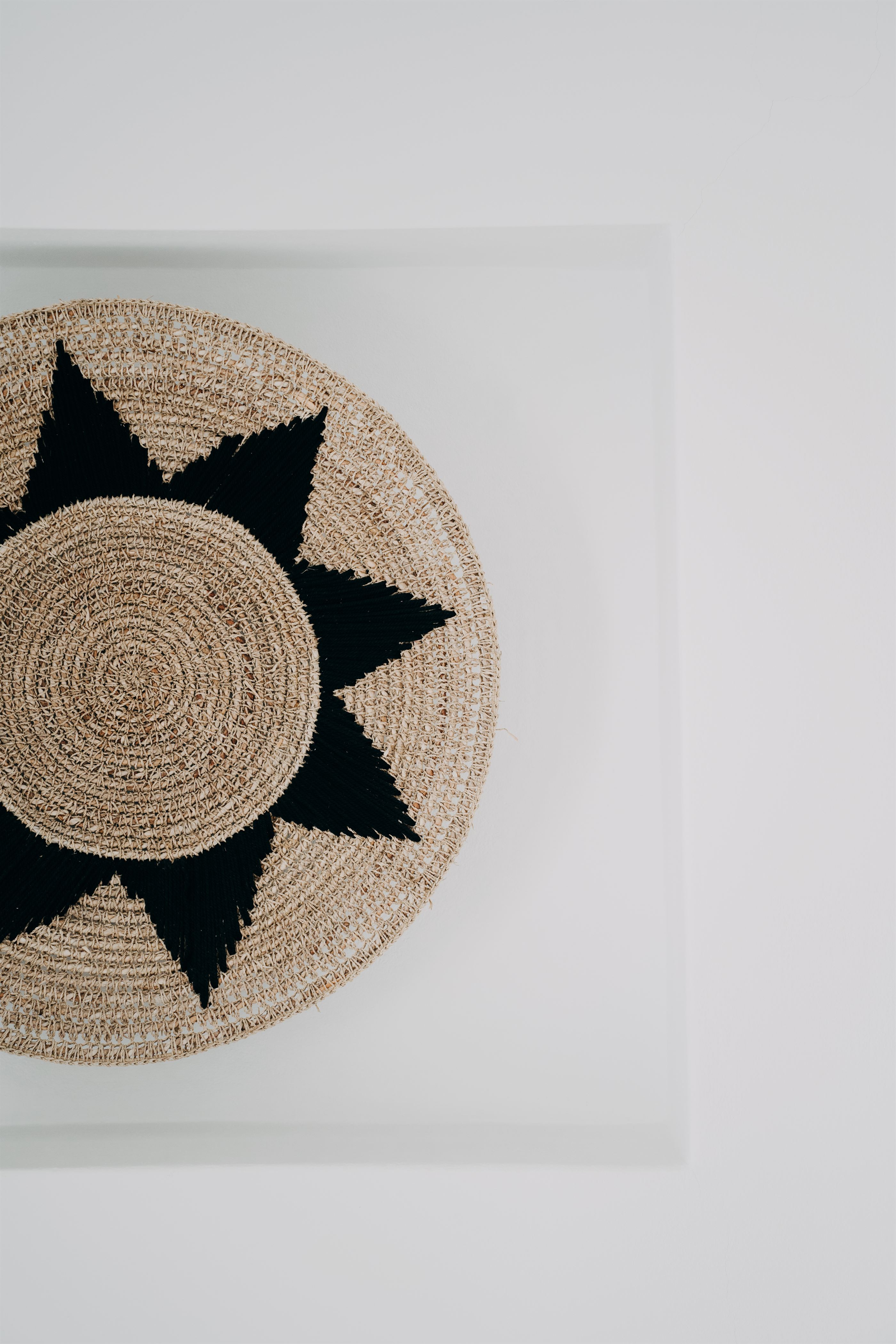 Handmade raffia wall piece against whitewashed stone
